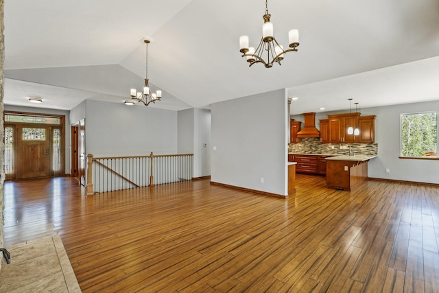 unfurnished living room with a chandelier, hardwood / wood-style floors, and lofted ceiling