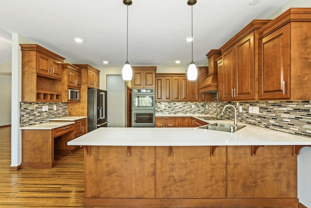 kitchen with kitchen peninsula, custom range hood, stainless steel appliances, sink, and decorative light fixtures