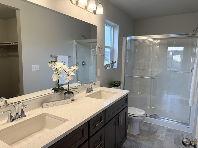 full bathroom with double vanity, a shower stall, toilet, and a sink