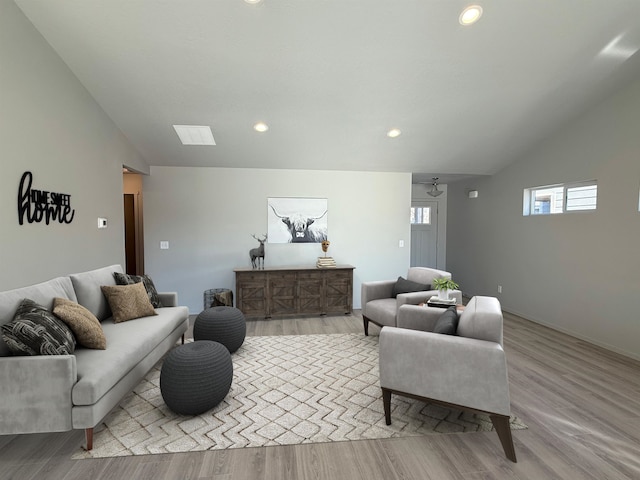 living room featuring recessed lighting, lofted ceiling with skylight, and wood finished floors