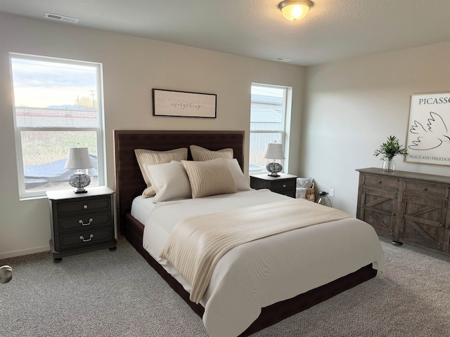 bedroom with visible vents and light carpet