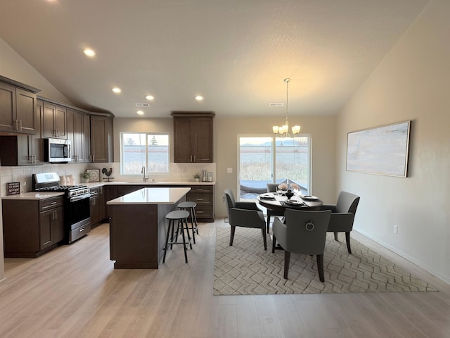 kitchen with backsplash, stainless steel appliances, lofted ceiling, and an inviting chandelier