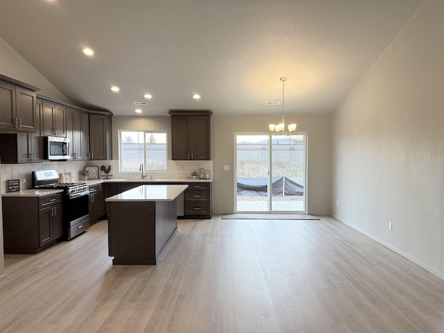 kitchen featuring a notable chandelier, stainless steel appliances, light countertops, decorative backsplash, and dark brown cabinets