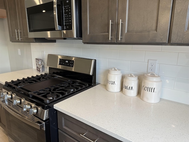 kitchen featuring dark brown cabinetry, stainless steel appliances, light stone counters, and tasteful backsplash