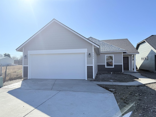 single story home featuring a garage, concrete driveway, and roof with shingles