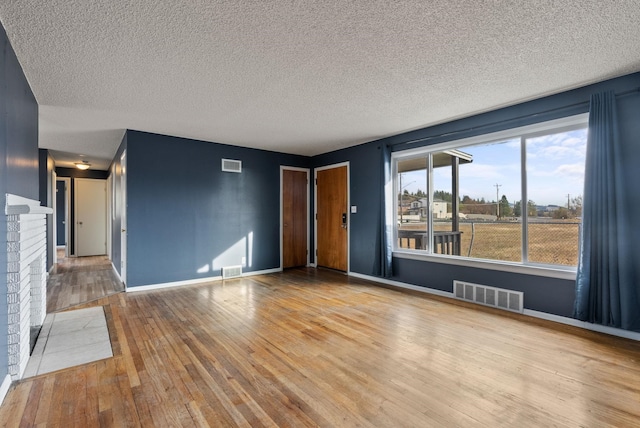 unfurnished living room featuring a fireplace, wood-type flooring, and a textured ceiling