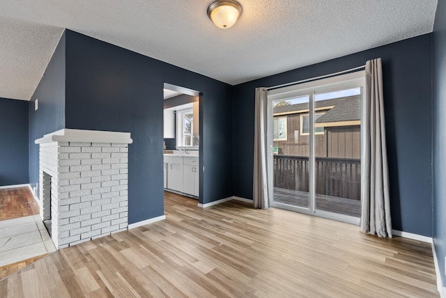 unfurnished living room with light hardwood / wood-style flooring, a healthy amount of sunlight, and a textured ceiling