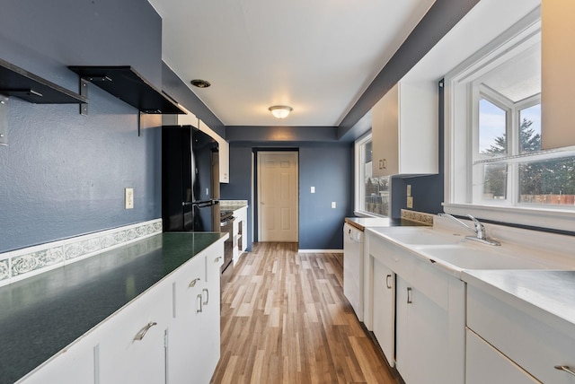 kitchen featuring black fridge, white cabinetry, light hardwood / wood-style flooring, and white dishwasher