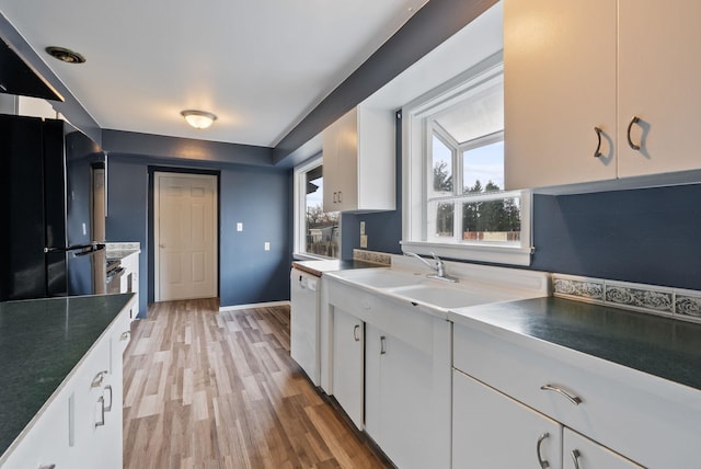 kitchen featuring black fridge, white dishwasher, white cabinetry, and light hardwood / wood-style floors