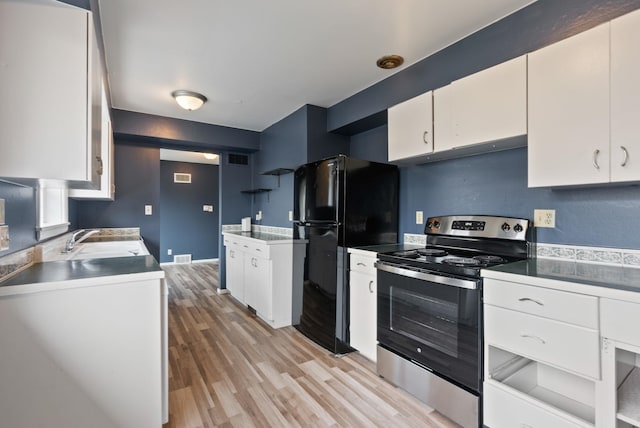 kitchen with light wood-type flooring, black fridge, stainless steel electric range oven, sink, and white cabinetry