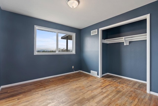 unfurnished bedroom with a closet and hardwood / wood-style flooring