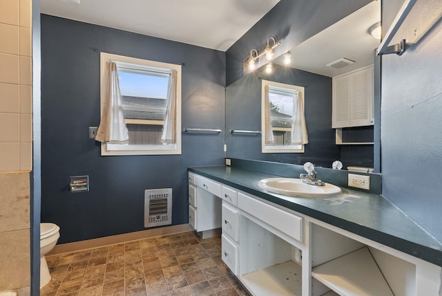 bathroom featuring vanity, heating unit, and toilet