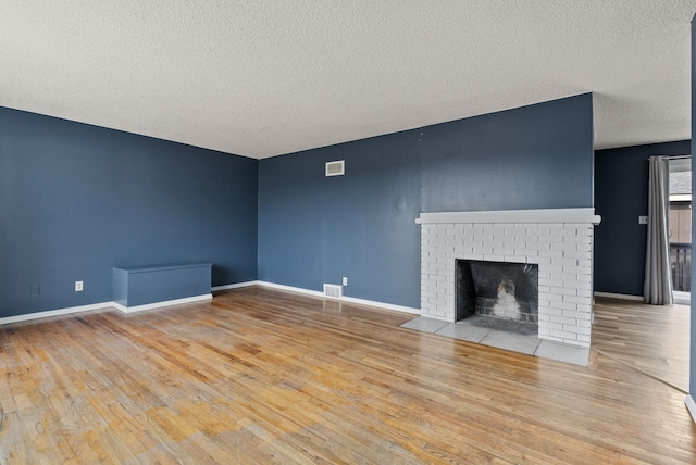 unfurnished living room with a fireplace, a textured ceiling, and light hardwood / wood-style flooring