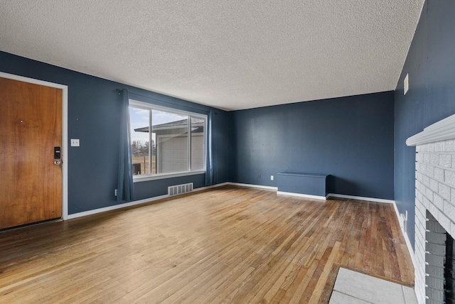 unfurnished living room with a textured ceiling, wood-type flooring, and a fireplace