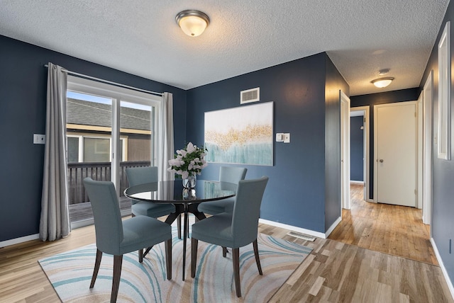 dining space with a textured ceiling and light hardwood / wood-style flooring