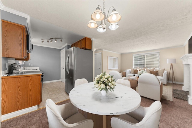 dining space featuring track lighting, an inviting chandelier, sink, crown molding, and a textured ceiling