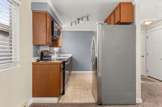 kitchen featuring rail lighting, a textured ceiling, stainless steel appliances, crown molding, and sink