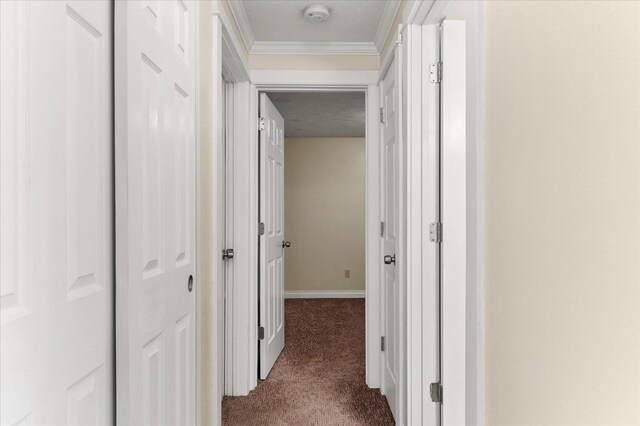 corridor featuring a textured ceiling, dark carpet, and crown molding