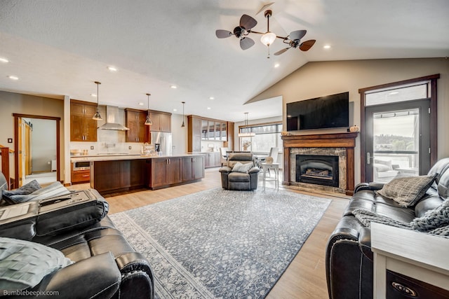 living room with ceiling fan, light hardwood / wood-style floors, and vaulted ceiling