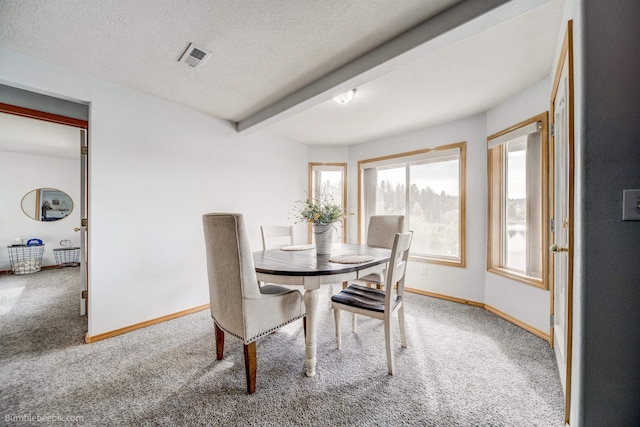 carpeted dining space with beam ceiling and a textured ceiling