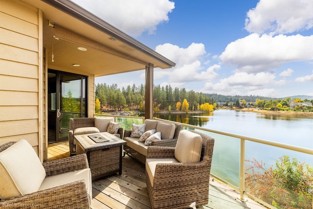 wooden deck featuring a water view and an outdoor living space with a fire pit