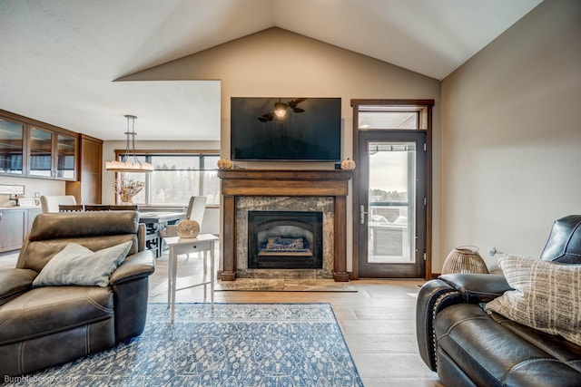 living room with a fireplace, light hardwood / wood-style flooring, and vaulted ceiling