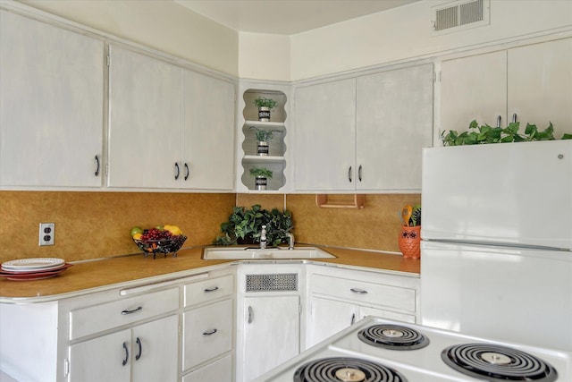 kitchen featuring white cabinets, sink, decorative backsplash, white fridge, and range