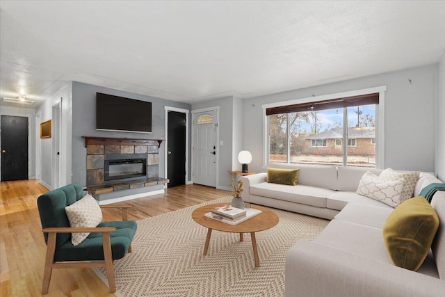 living room featuring a stone fireplace, a textured ceiling, and light hardwood / wood-style flooring