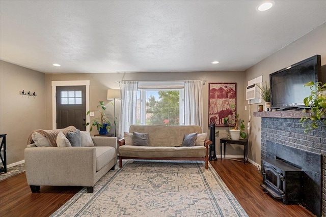 living room with a textured ceiling, hardwood / wood-style flooring, a wood stove, and plenty of natural light