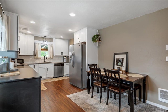 kitchen featuring sink, dark hardwood / wood-style floors, tasteful backsplash, white cabinetry, and stainless steel appliances