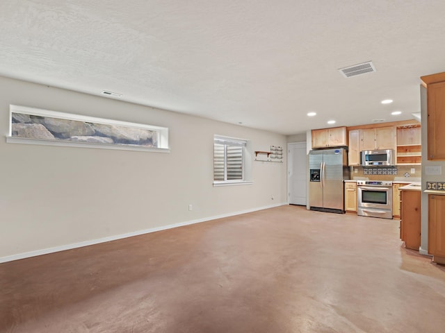 kitchen with light brown cabinets, backsplash, and appliances with stainless steel finishes