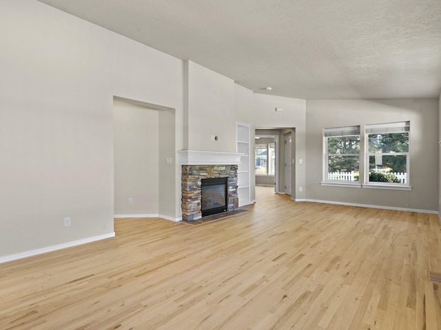 unfurnished living room with a textured ceiling, light wood-type flooring, and a fireplace