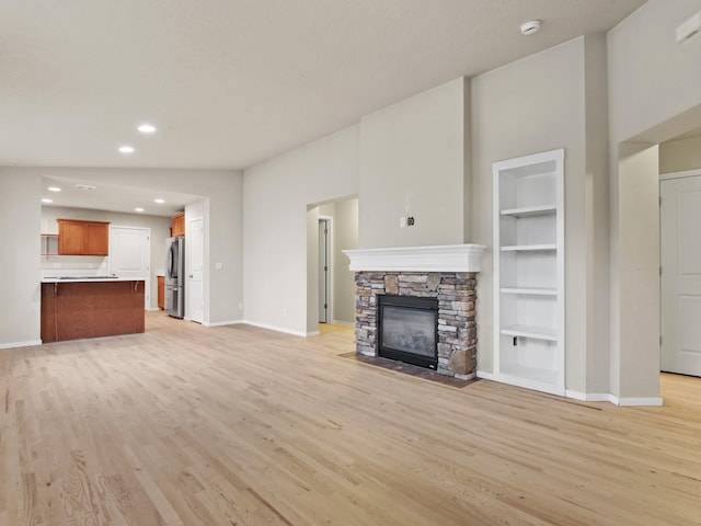 unfurnished living room featuring a fireplace, light hardwood / wood-style flooring, and built in features