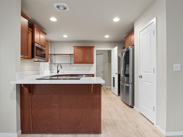 kitchen featuring a kitchen bar, kitchen peninsula, light hardwood / wood-style floors, and appliances with stainless steel finishes