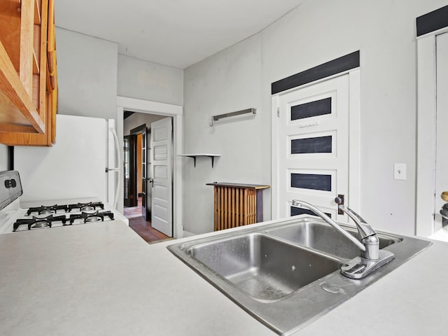 kitchen featuring gas range, white fridge, and sink