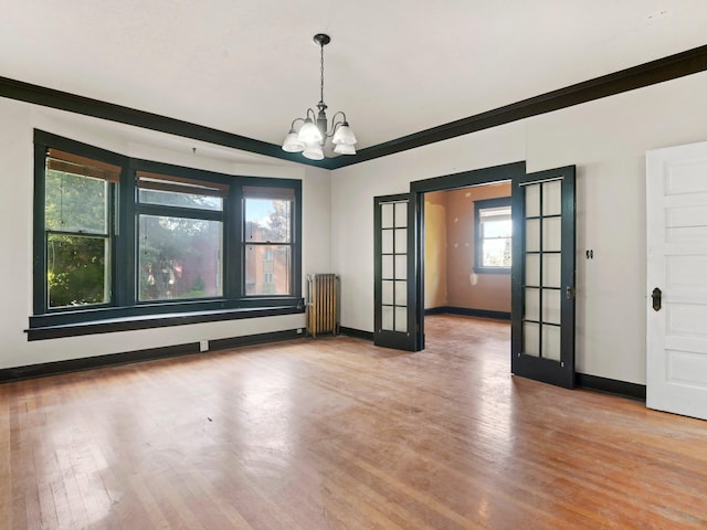 unfurnished dining area with french doors, radiator, ornamental molding, wood-type flooring, and a notable chandelier