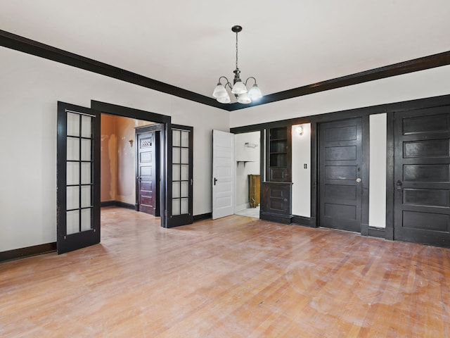 spare room with an inviting chandelier, ornamental molding, light hardwood / wood-style flooring, and french doors