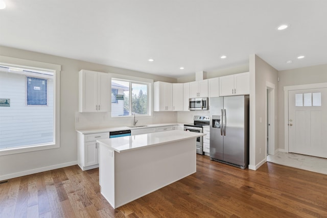 kitchen featuring dark hardwood / wood-style flooring, stainless steel appliances, sink, white cabinetry, and a kitchen island