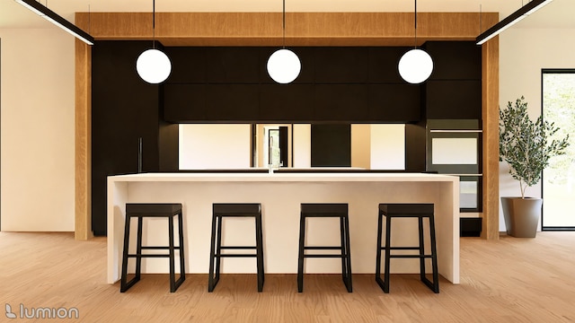 kitchen with a kitchen bar, hanging light fixtures, and light hardwood / wood-style floors