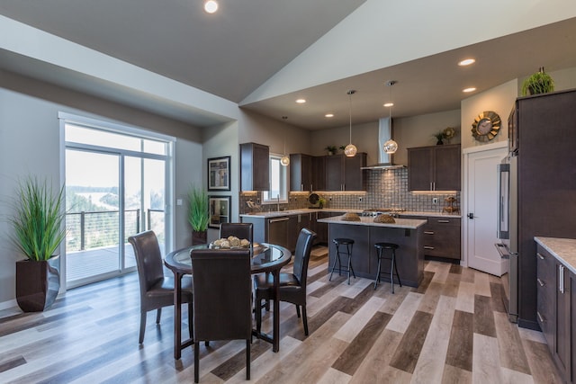 dining area featuring light wood-style floors, recessed lighting, and high vaulted ceiling