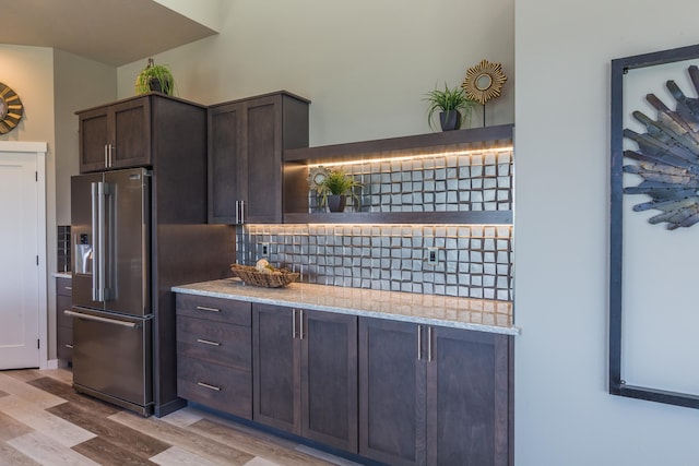 kitchen with light wood-style flooring, dark brown cabinetry, high end fridge, decorative backsplash, and open shelves