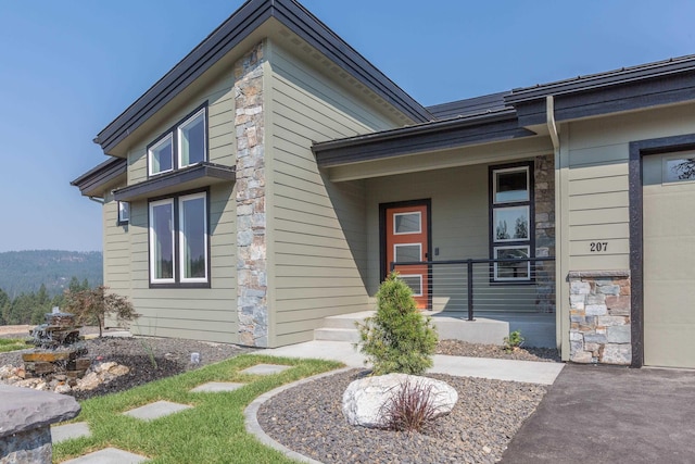 exterior space with a garage, stone siding, and a porch