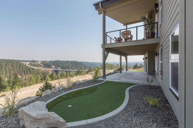 view of yard with a balcony, a forest view, and a patio