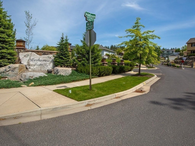 view of road featuring traffic signs, a residential view, curbs, and sidewalks