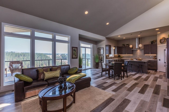 living area with high vaulted ceiling, recessed lighting, and wood finished floors