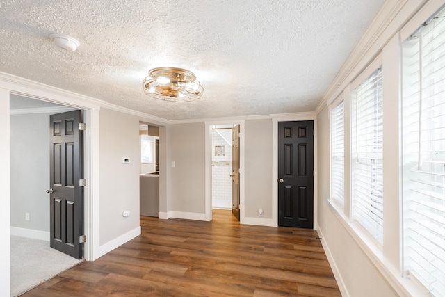 empty room with a textured ceiling, dark hardwood / wood-style flooring, and crown molding