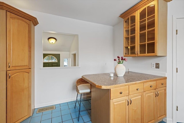 kitchen with tile patterned floors, a breakfast bar, kitchen peninsula, and vaulted ceiling