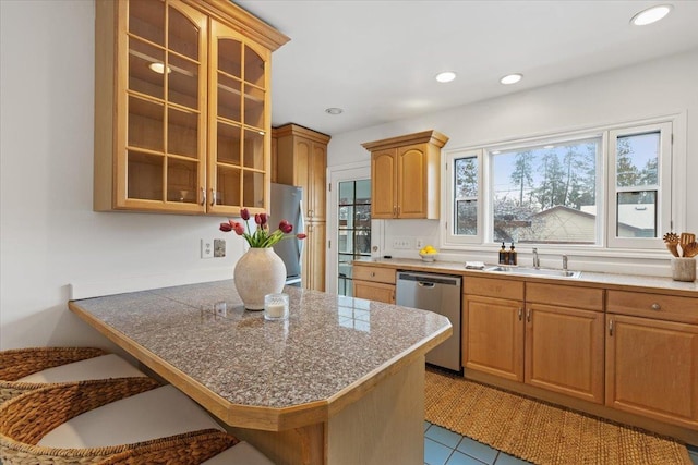 kitchen featuring kitchen peninsula, appliances with stainless steel finishes, light tile patterned floors, and sink