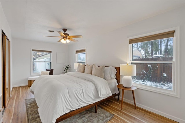 bedroom featuring multiple windows, light hardwood / wood-style floors, and ceiling fan