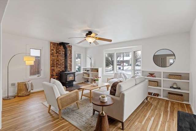 living room with ceiling fan, light wood-type flooring, and a wood stove